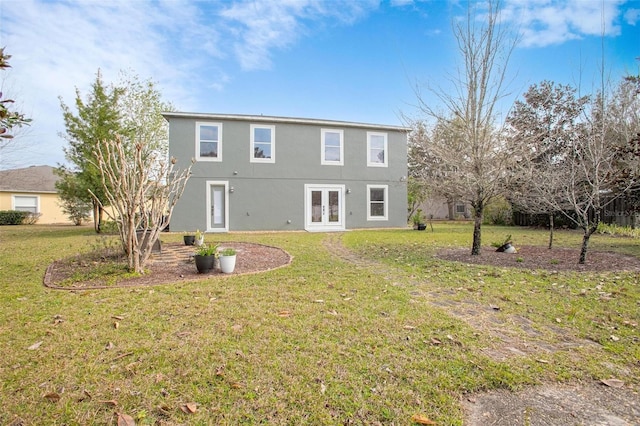 back of property with french doors, a yard, and stucco siding