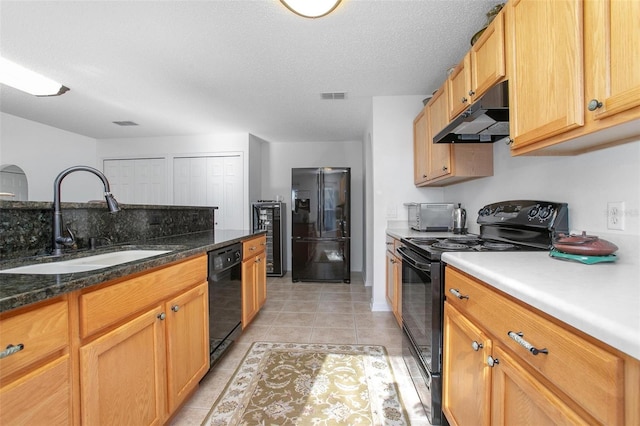 kitchen featuring visible vents, under cabinet range hood, black appliances, a sink, and light tile patterned flooring