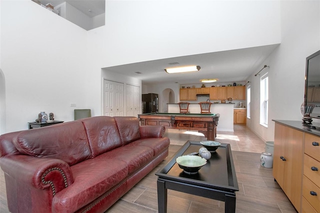 living room with arched walkways, pool table, and a high ceiling