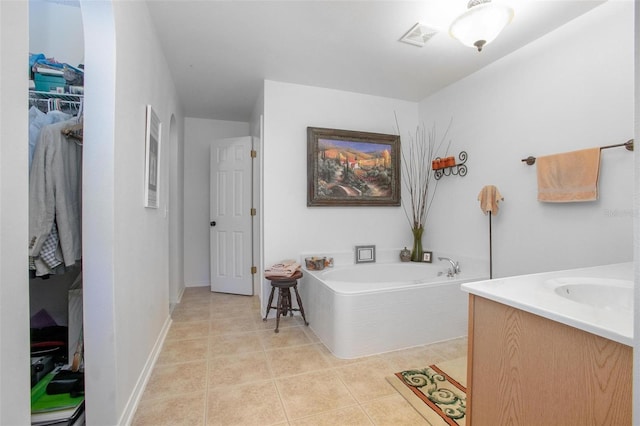 full bathroom featuring baseboards, visible vents, tile patterned floors, a garden tub, and a walk in closet