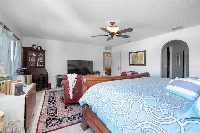 bedroom with arched walkways, wood finished floors, visible vents, and a ceiling fan