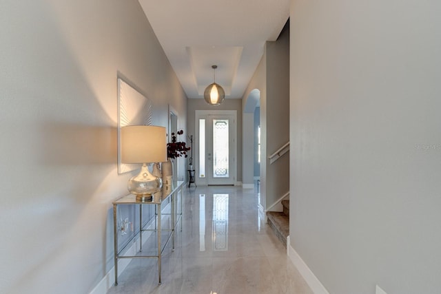 foyer featuring stairway, baseboards, and arched walkways