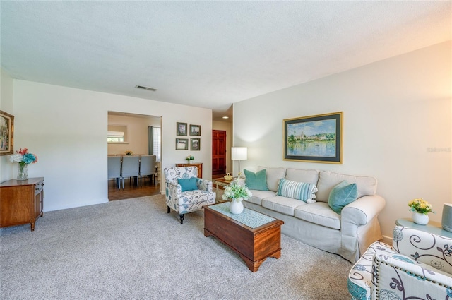 living room featuring visible vents, a textured ceiling, and carpet flooring