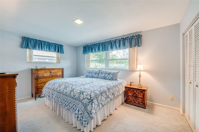 carpeted bedroom featuring multiple windows, a closet, and baseboards