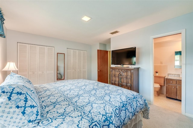 bedroom featuring carpet floors, visible vents, two closets, and ensuite bathroom