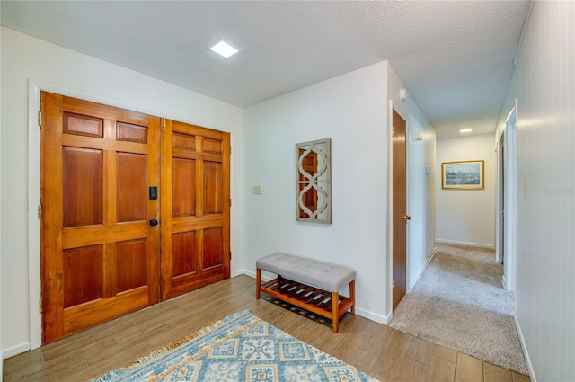 entryway featuring a textured ceiling, baseboards, and wood finished floors