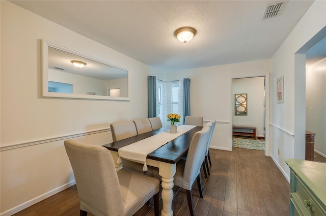 dining area featuring visible vents, dark wood finished floors, a textured ceiling, and baseboards