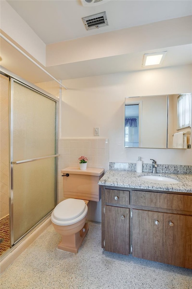 full bathroom with speckled floor, a shower stall, visible vents, and tile walls