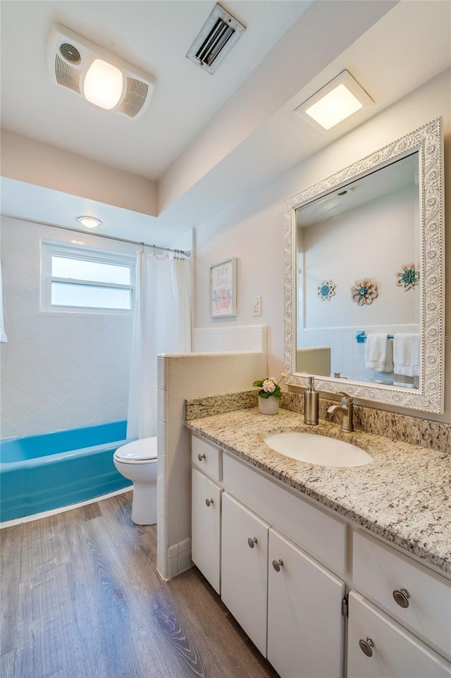 bathroom with shower / tub combo with curtain, visible vents, toilet, vanity, and wood finished floors