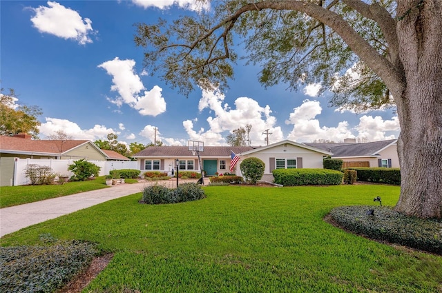 ranch-style home featuring driveway, fence, and a front lawn