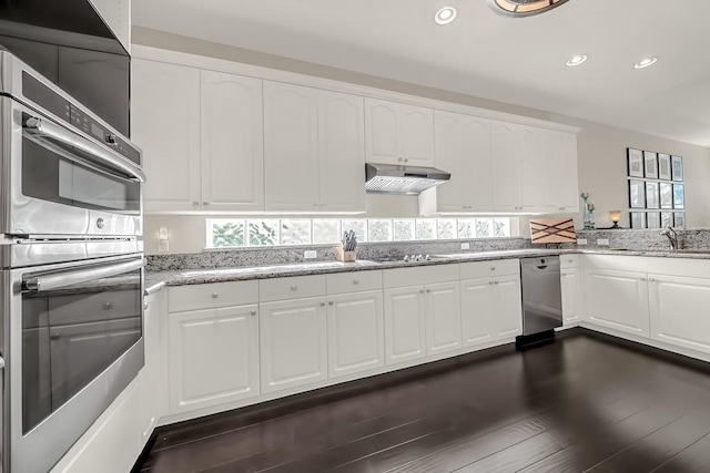 kitchen featuring light stone countertops, under cabinet range hood, appliances with stainless steel finishes, and a sink