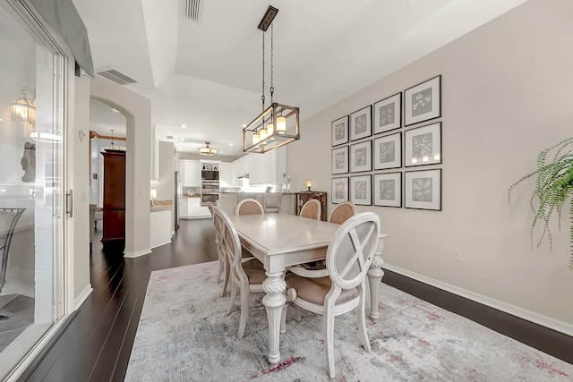 dining space with dark wood-style floors, baseboards, visible vents, and arched walkways