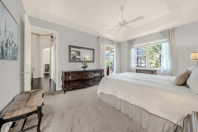 bedroom with carpet, a raised ceiling, and ceiling fan