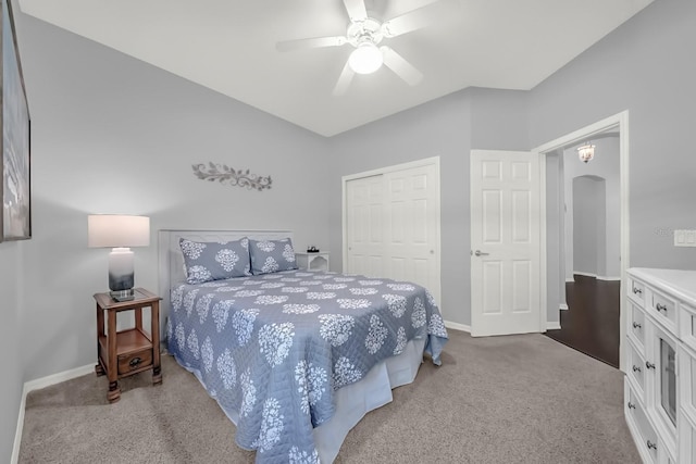 carpeted bedroom with arched walkways, ceiling fan, a closet, and baseboards