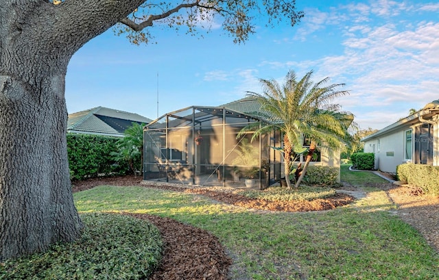 back of house with glass enclosure and a lawn