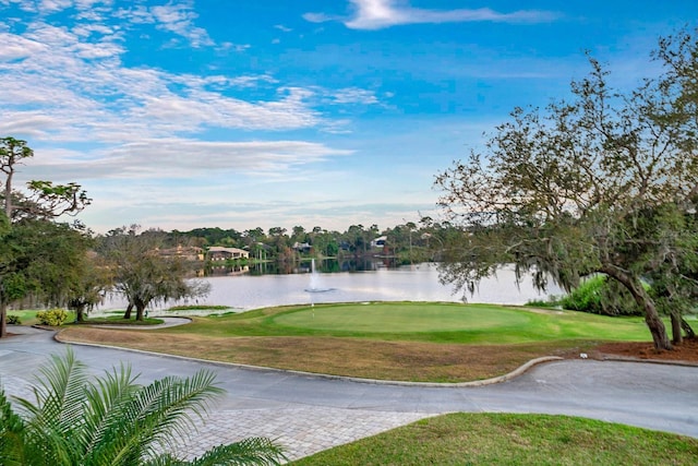 view of property's community with a yard, golf course view, and a water view