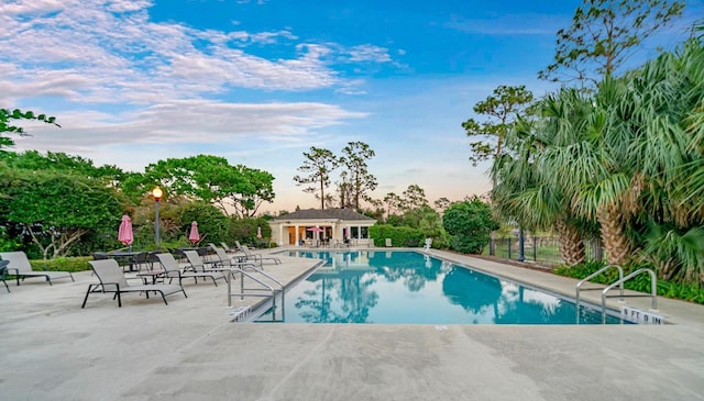 community pool with a patio area and fence