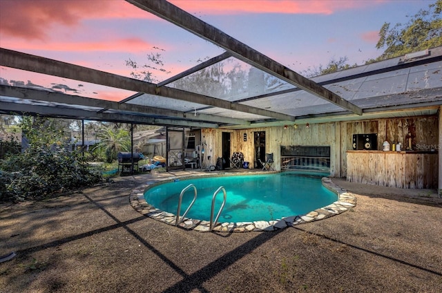 pool at dusk featuring a patio, a lanai, and an outdoor pool