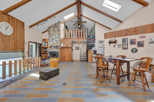 interior space featuring high vaulted ceiling, a fireplace, a skylight, and beam ceiling