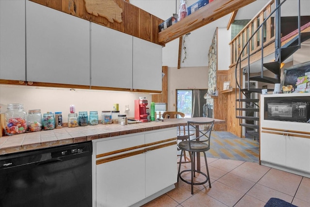 kitchen featuring tile counters, white cabinets, dishwasher, a high ceiling, and light tile patterned flooring