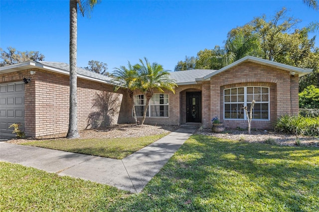 ranch-style house with a front yard, brick siding, and an attached garage