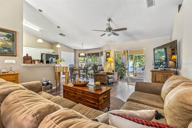 living area with visible vents, vaulted ceiling, a textured ceiling, and wood finished floors