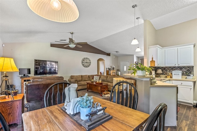 dining room with arched walkways, ceiling fan, a textured ceiling, lofted ceiling, and dark wood finished floors