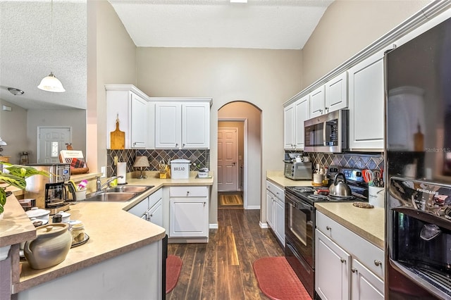 kitchen with arched walkways, dark wood-type flooring, a sink, white cabinetry, and black appliances