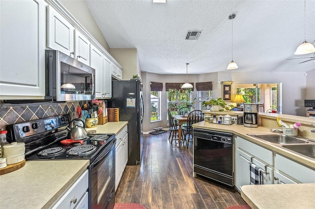 kitchen featuring dark wood-style floors, black appliances, light countertops, and visible vents