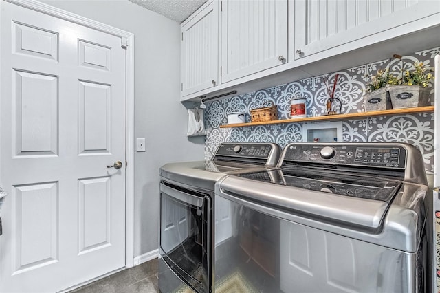 clothes washing area featuring cabinet space, baseboards, dark tile patterned flooring, a textured ceiling, and washing machine and dryer