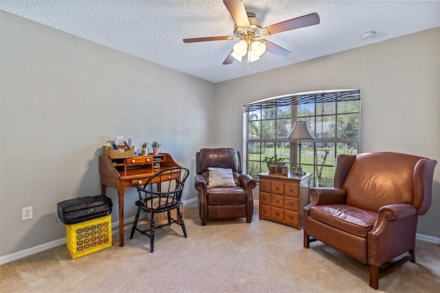 sitting room featuring light colored carpet, ceiling fan, a textured ceiling, and baseboards