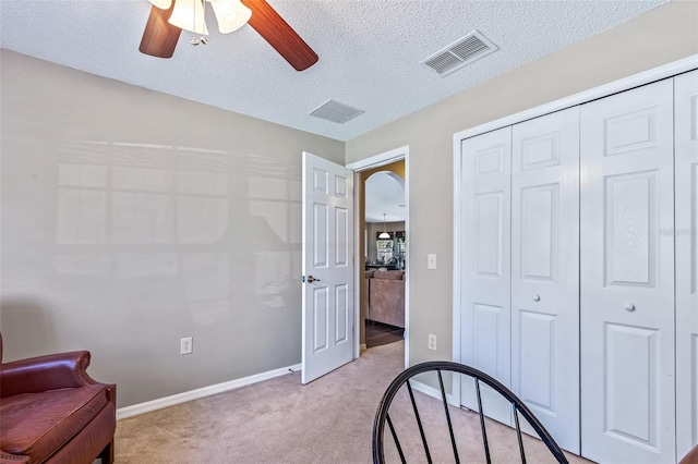 bedroom with baseboards, visible vents, light colored carpet, a textured ceiling, and a closet