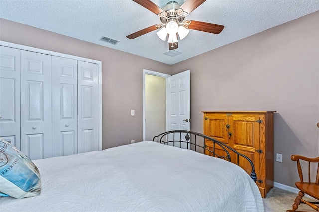 carpeted bedroom featuring a closet, visible vents, a ceiling fan, a textured ceiling, and baseboards