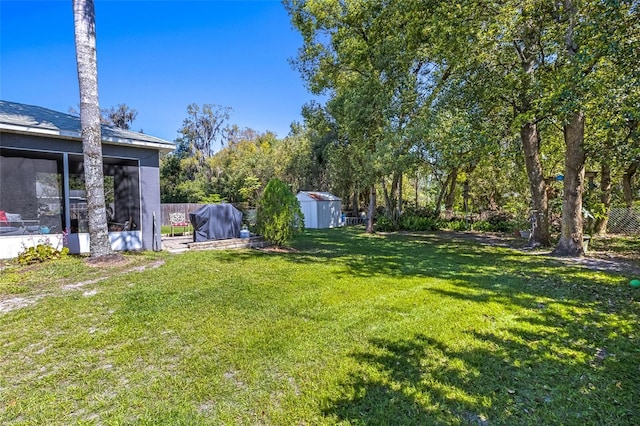 view of yard featuring an outbuilding, a sunroom, fence, and a storage unit