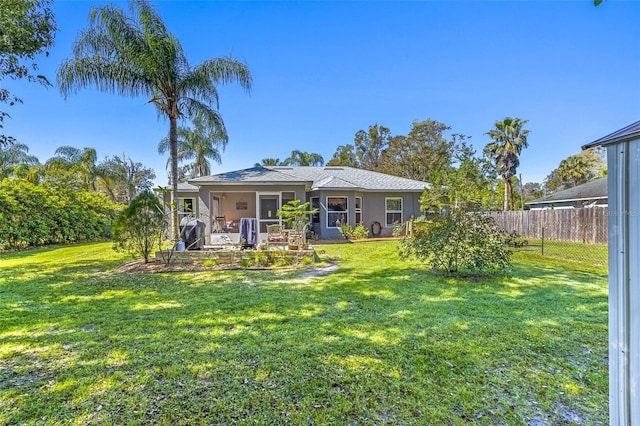 rear view of property with stucco siding, fence, and a yard