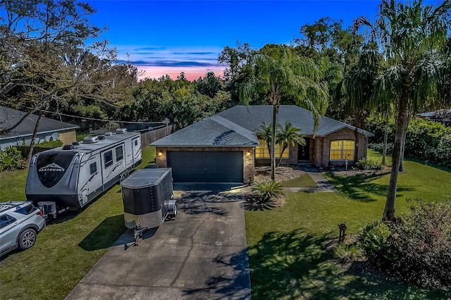 view of front of home featuring a front yard, brick siding, driveway, and an attached garage