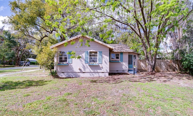 rear view of property with a shingled roof, a lawn, entry steps, crawl space, and fence