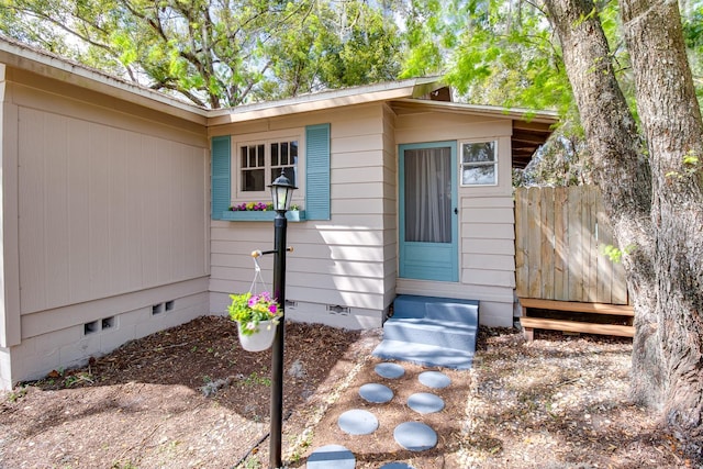 doorway to property featuring crawl space and fence