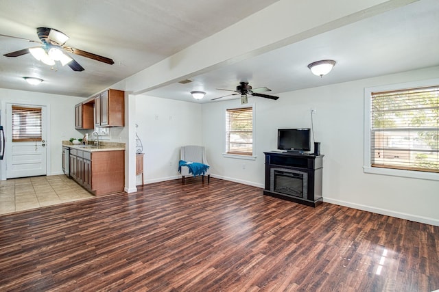 kitchen with light countertops, a glass covered fireplace, open floor plan, wood finished floors, and baseboards