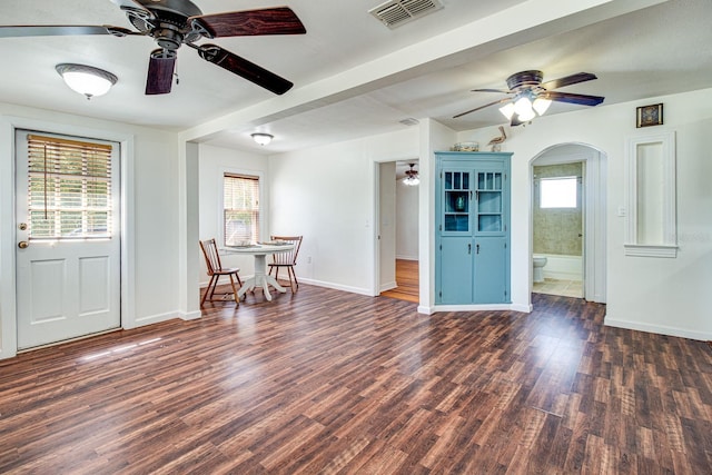 interior space featuring arched walkways, visible vents, baseboards, and wood finished floors