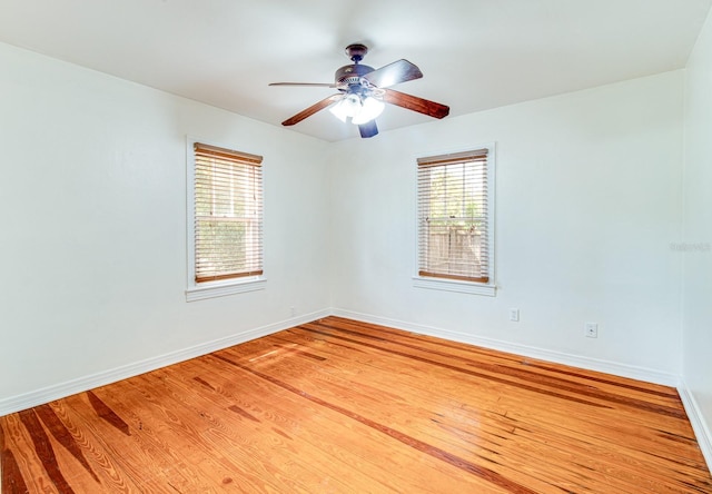 spare room with ceiling fan, light wood-type flooring, and baseboards