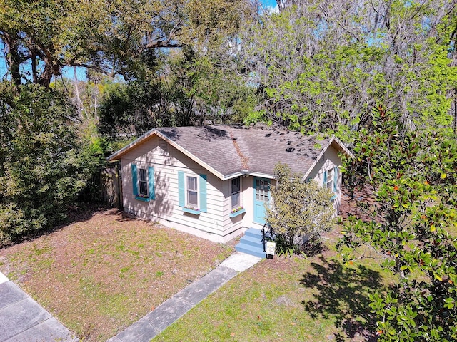 view of front of home with a front lawn and a shingled roof