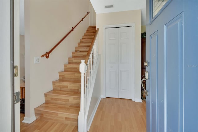 foyer featuring light wood finished floors, stairway, and visible vents