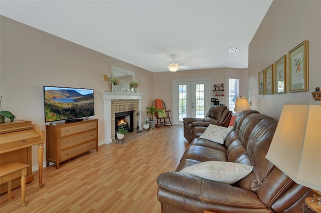 living area with light wood-type flooring, a brick fireplace, visible vents, and french doors