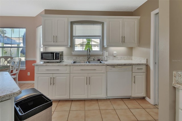 kitchen featuring light tile patterned floors, dishwasher, stainless steel microwave, light countertops, and a sink