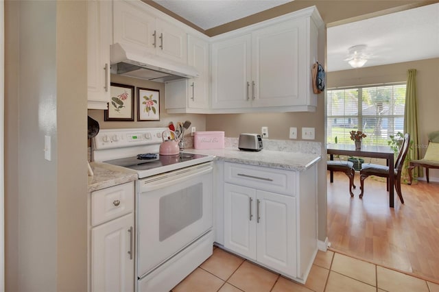 kitchen featuring under cabinet range hood, white range with electric stovetop, white cabinets, and light tile patterned flooring