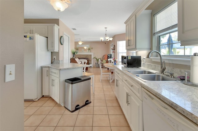 kitchen with light tile patterned floors, light countertops, a sink, white appliances, and ceiling fan with notable chandelier