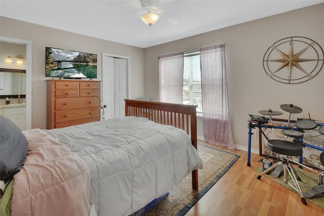 bedroom featuring a closet, ensuite bath, wood finished floors, and baseboards