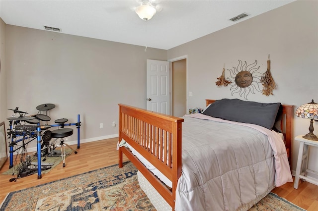 bedroom with baseboards, visible vents, and wood finished floors