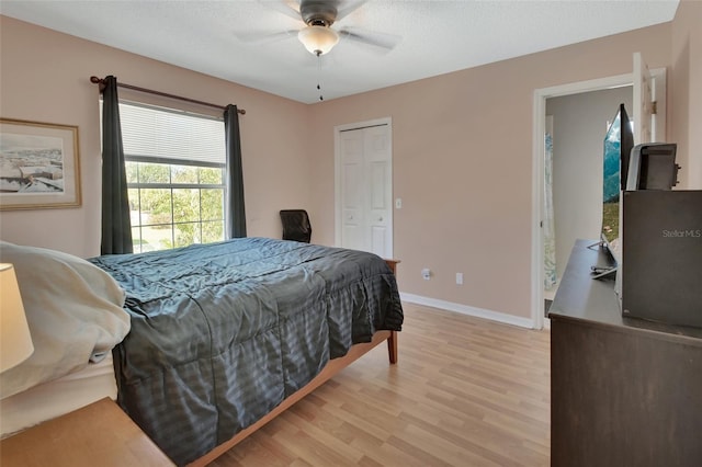 bedroom with a closet, light wood-style flooring, a ceiling fan, a textured ceiling, and baseboards